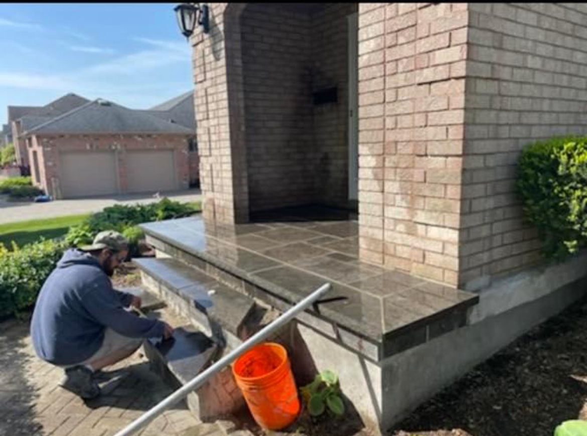 Restored front porch and steps with new dark stone tiles and clean grout lines after professional masonry work in London Ontario